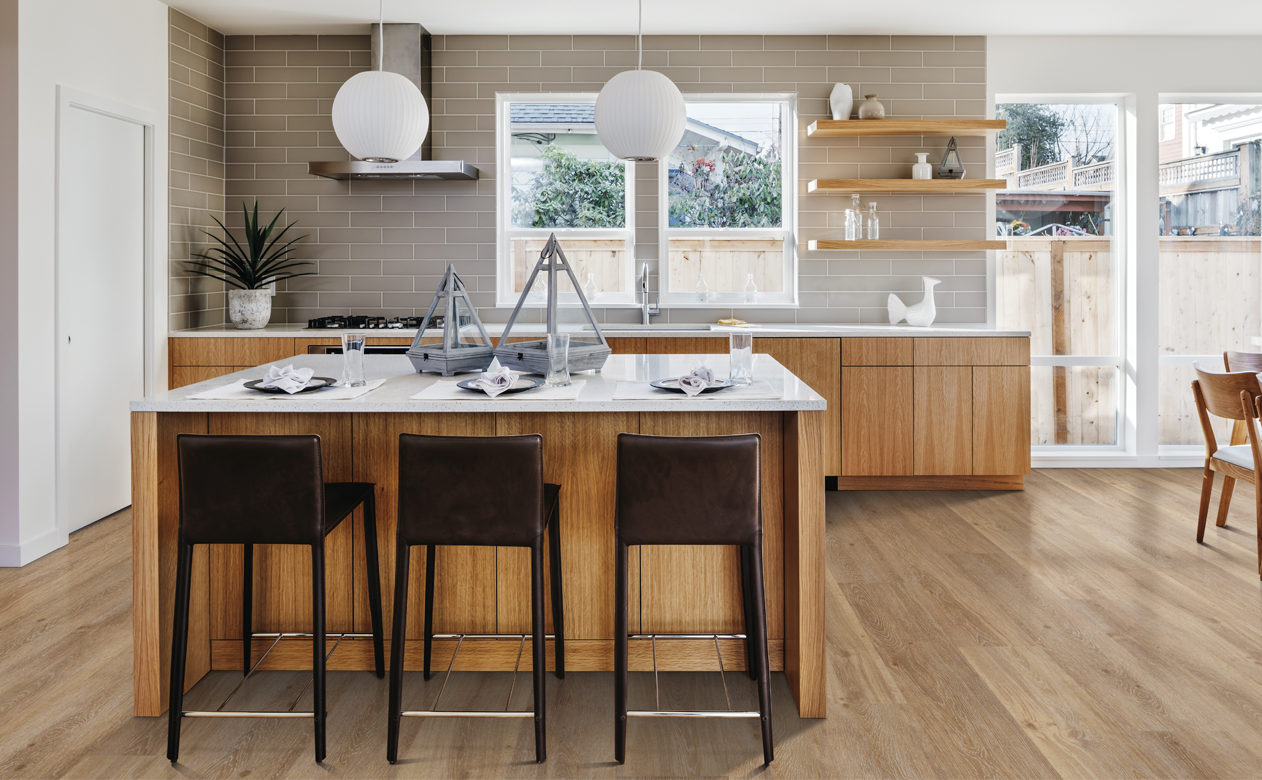 light wood flooring in kitchen with white stone countertops and brown stools